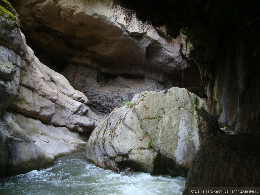 Вид на бурлящий поток реки из пещеры