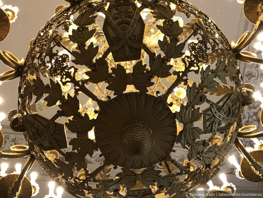Фельдмаршальский зал (1833-1834) автор Огюст Монферран. Очень примечателен декор люстры, что представляет собой изображения трофеев и лаврового венка, выполненный из золоченой бронзы.
