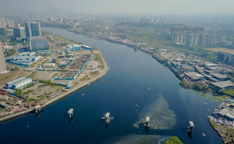 Этот мост соединит комплекс Бандра Курла с несколькими транспортными развязками на противоположной стороне реки Митхи. Эта река представляет собой крайний разрыв в богатстве в Мумбаи. Здание слева крупнейшая компания получения прибыли Индии. Справа находится край трущоб Дхарави, когда-то самый большой в Индии, и место для фильма Миллионер из трущоб.  