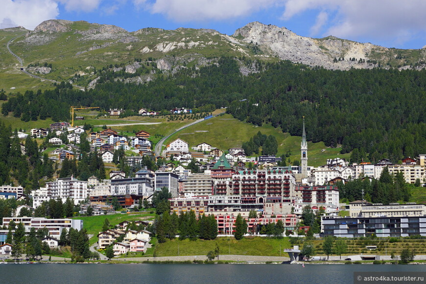 За городом видна железная дорога, по которой проходит альпийский панорамный поезд.