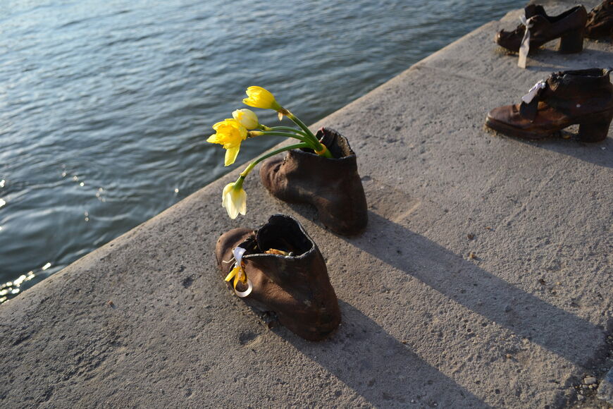 Посетители оставляют в чугунных ботинках цветы и конфеты