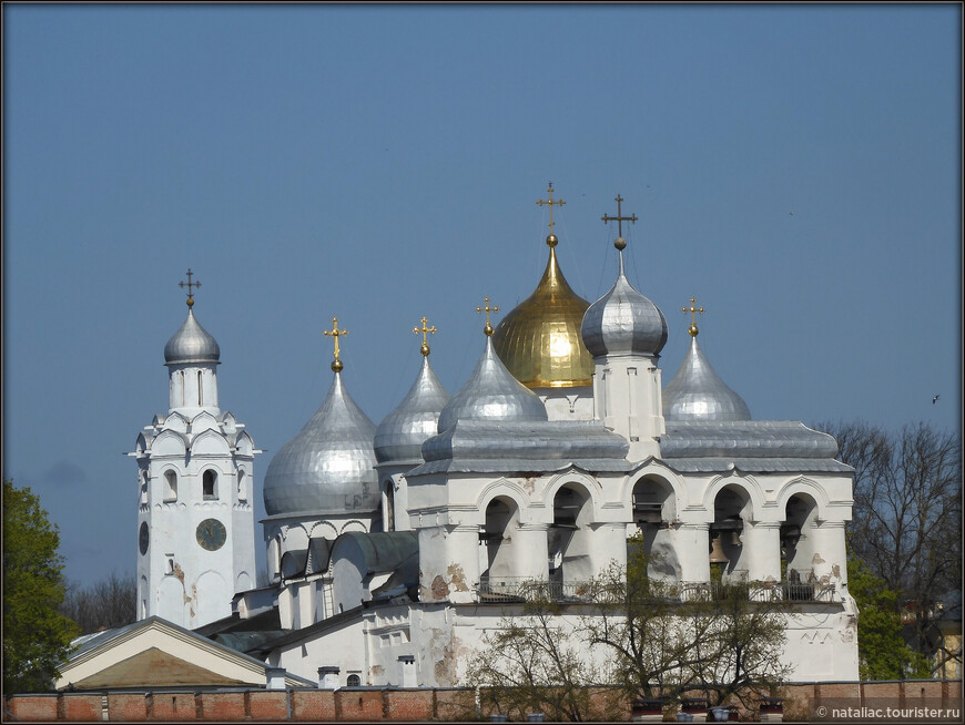 Вид с Торговой стороны, с берега Волхова, слева - направо: Часовая башня, на переднем плане - Звонница, а за нею видны купола Софийского собора. 