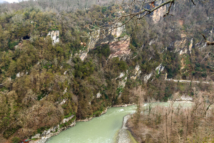 Ахштырская пещера в скалистом берегу реки (слева)