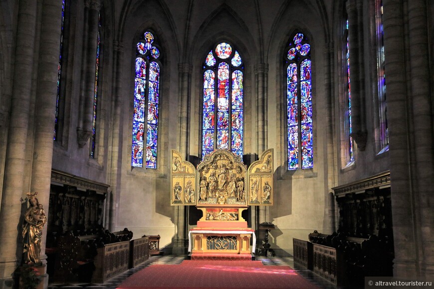 Главный алтарь с витражами XX века и позолоченным резным триптихом XV века.