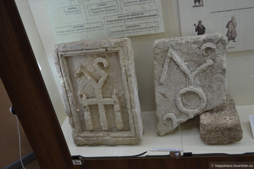При раскопках западных ворот рядом были обнаружены две плиты.Мраморная с надписью о восстановлении городских ворот в 229 г. и известняковая с рельефным именным знаком боспорских царей.