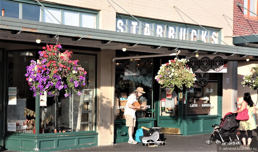 Уличный музыкант у самой первой в Штатах кофейни Старбакс, открытой в 1971 г. на территории рынка Пайк Плейс. Фото 2011 года. Кстати, Старбакс - не единственная кофейная компания, рожденная в Сиэтле, за что он носит также и имя город кофе