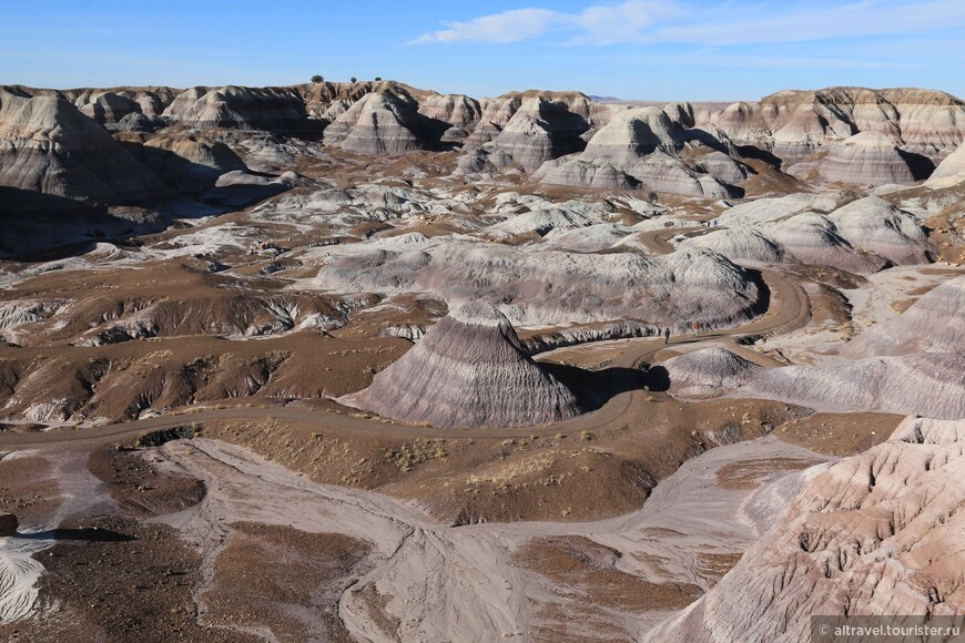 Вид сверху на «плохие земли» под названием «Голубое плоскогорье» (Blue Mesa). Внизу видны фигурки идущих по тропе людей.