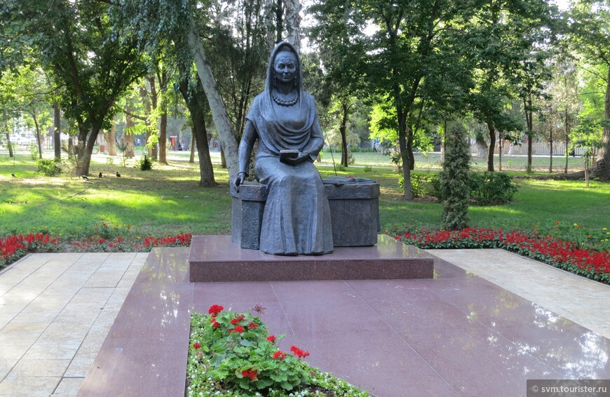 Поэтесса Алиева изображена сидящей на скамье.Она одета в длинное платье,голова покрыта шалью.На странице открытой книги,лежащей рядом,можно прочесть принадлежащие ей проникновенные поэтические строки.