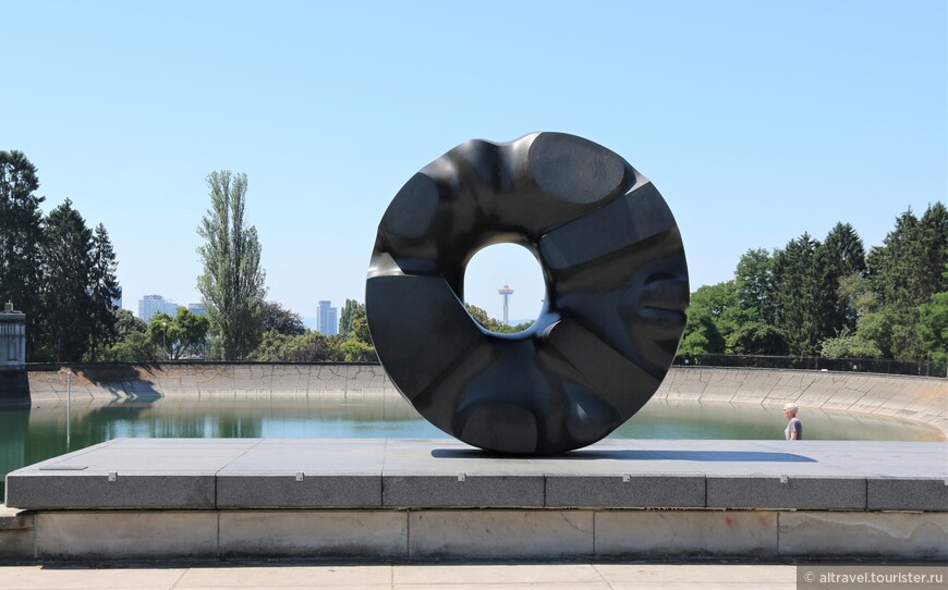 Скульптура Черное солнце Исаму Ногучи (в просторечии именуемая «Пончик»), сквозь которую видно Космическую иглу.