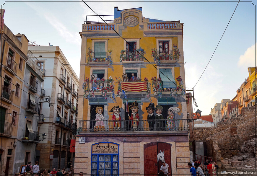 Дом с нарисованным фасадом, приветливо встречающий всех своих гостей на Plaça dels Sedassos  
