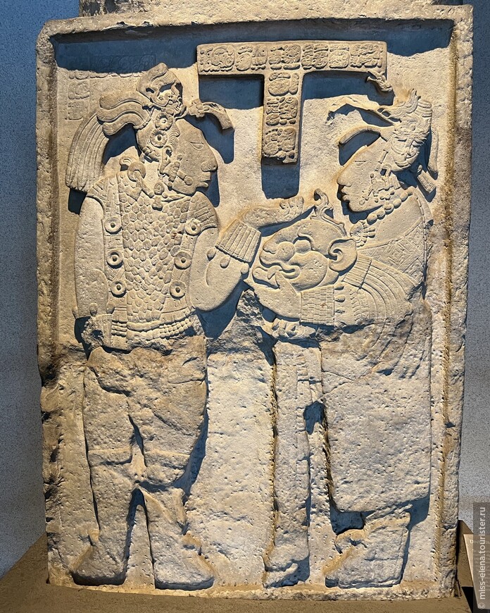 Зал майя. Стелла майя из Ясчилана: Кабаль Хоок вручает своему мужу, царю Итцамнаю Баламу III, шлем в виде головы ягуара.