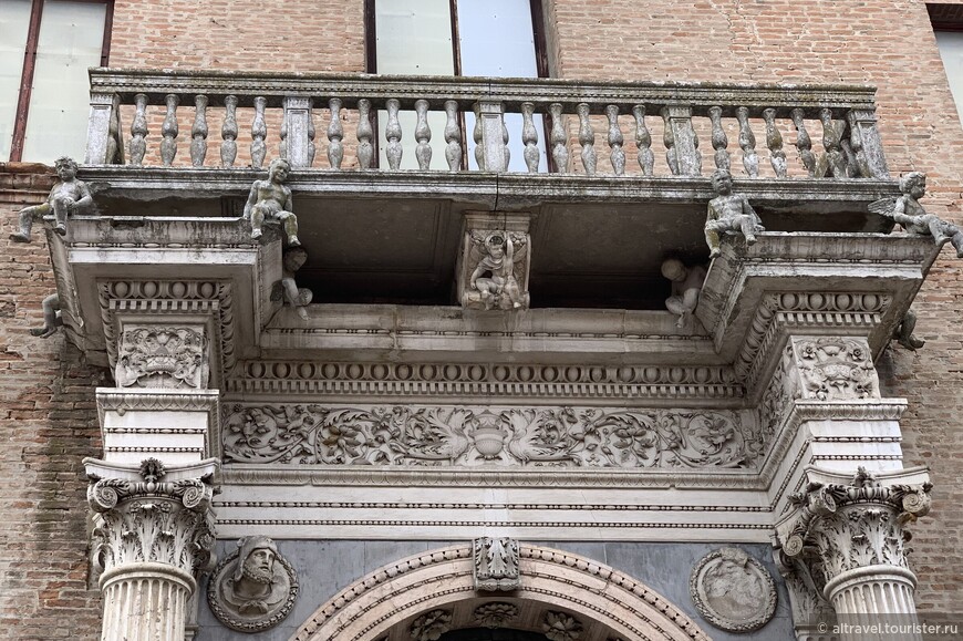  Над порталом возвышается белый мраморный балкон, поддерживаемый путти (заставили детей работать!). Под балконом видны два круга, в левом из которых находится бюст Геракла со шкурой Немейского льва, недвусмысленный намёк на Эрколе I д'Эсте.