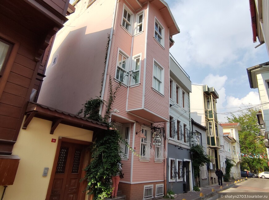 В розовом и зеленом домиках с левой стороны улицы находятся апартаменты