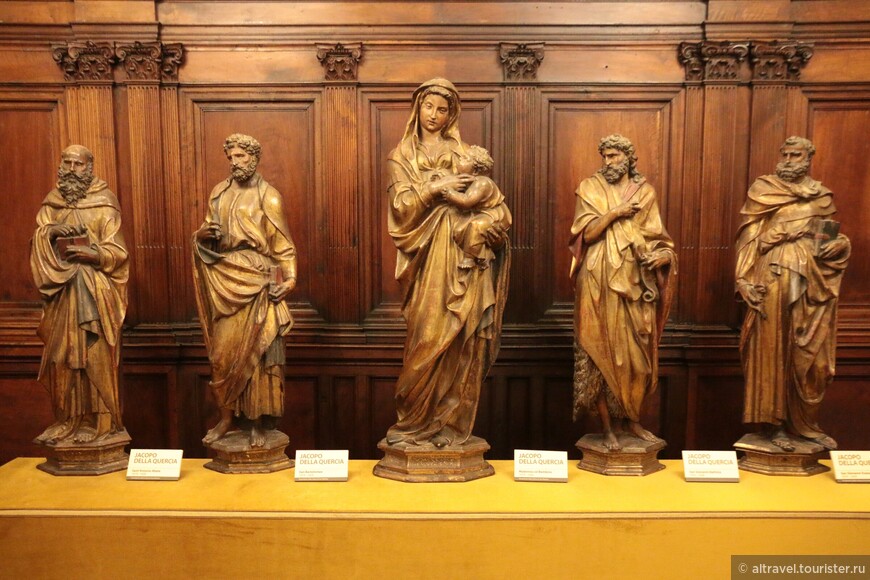 Группа из пяти деревянных позолоченных статуй традиционно считается работой знаменитого сиенского скульптора Якопо делла Кверча (1371-1438).