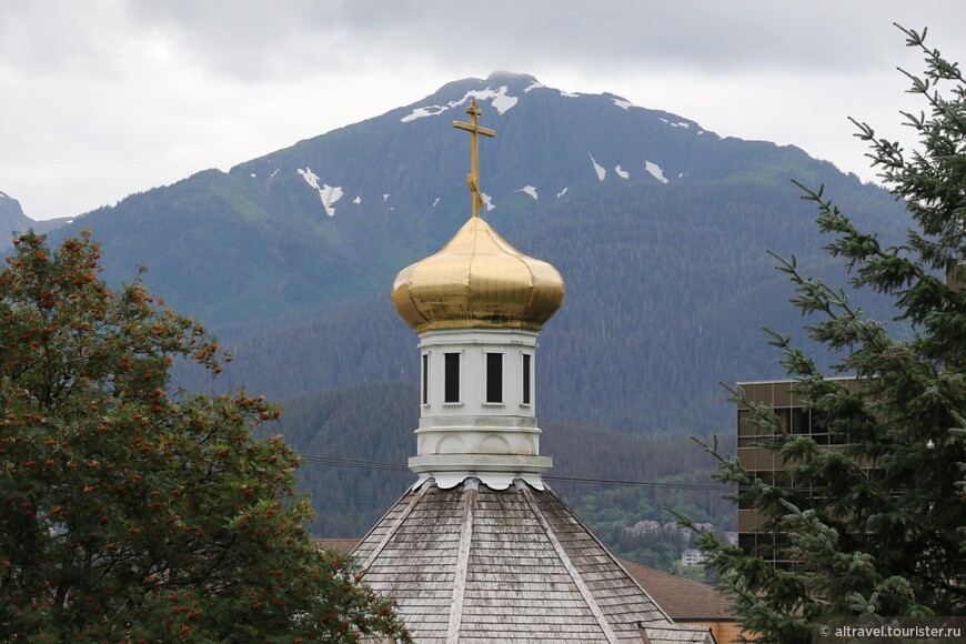 Луковичная глава церкви на фоне окружающих гор.