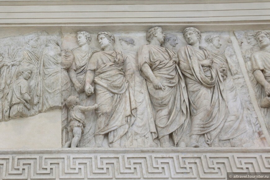 На этом рельефе с членами императорской семьи головы не сохранились и были воссозданы в ходе реставрации. Идентификация персонажей затруднена, но считается, что первая фигура справа, напоминающая женщину - либо сестра Августа Октавия, либо его жена Ливия.