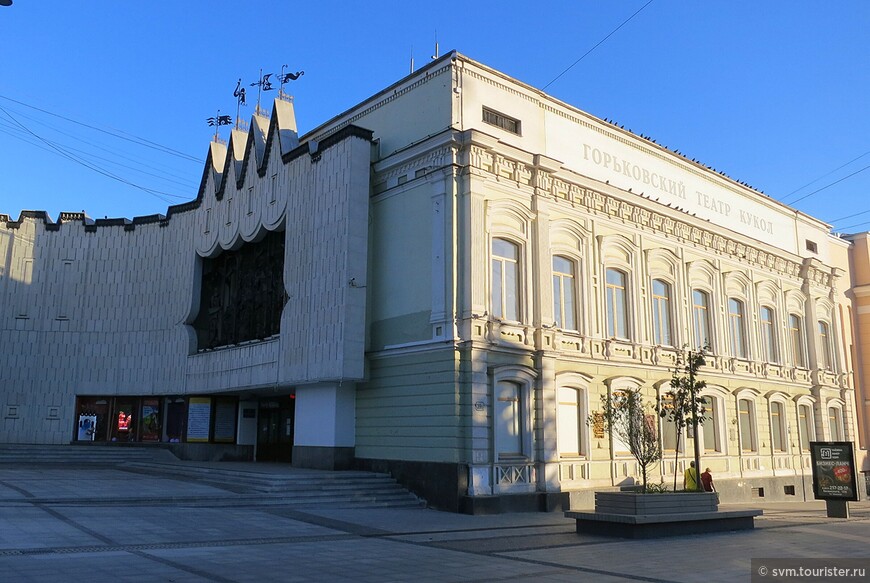 Вход в кукольный театр выполнен в виде стилизованного портала сцены,на которой,по старинному русскому обычаю,разыгрывают представление зазывалы-выкованные из меди шарманщик,петрушки и их помошники.