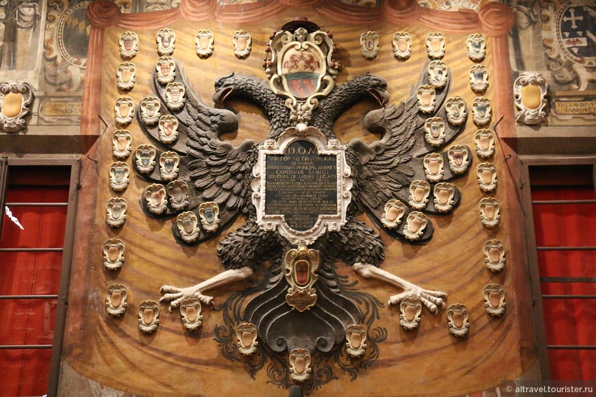 Двуглавый орёл на этом мемориале, посвященном кардиналу-легату Фабрицио Савелли (1607-1659), позаимствован с герба Священной Римской империи германской нации. Герб самого кардинала расположен между головами орла с красной кардинальской шляпой наверху. Столь внушительного орла кардинал Фабрицио заслужил за покровительство немецким студентам.

