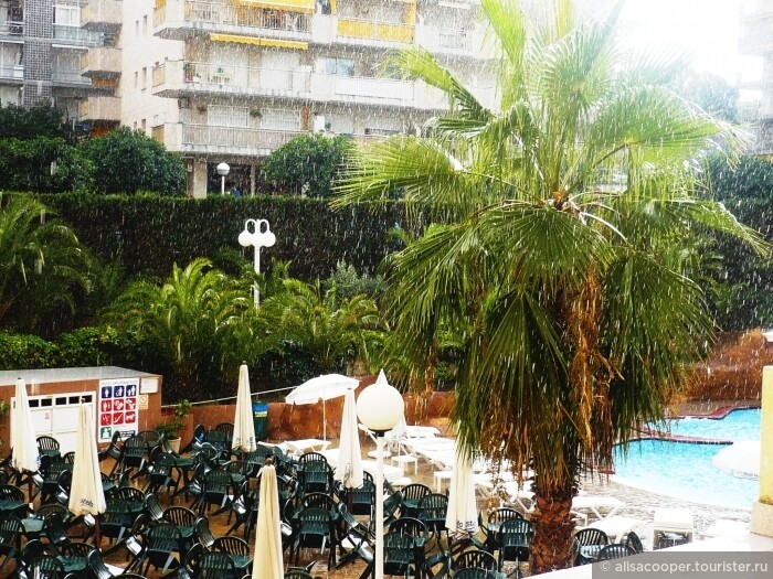 внутренний двор отеля с кафе и бассейном во время тропического ливня