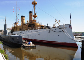 Крейсер "Аврора".
На самом деле это броненосец "Олимпия", принимавший участие еще в Испано-американской войне 1898 года.
Рядом примостилась подводная лодка "Бекуна", спущенная на воду в 1944 году.
