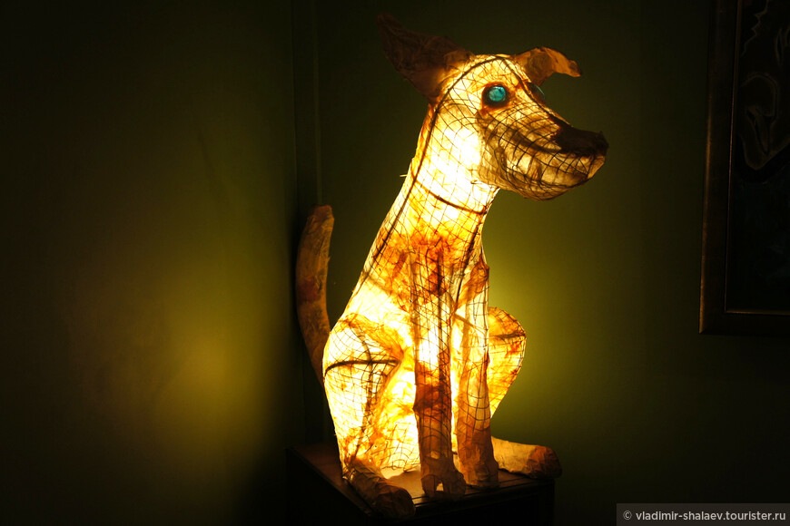 В углу зала сидит самая главная собака кафе, выполненная в стиле абажура со светящимся нутром и зелёными глазами.