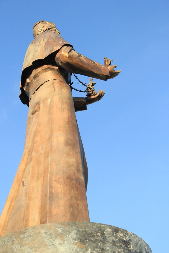 статуя Сан Витореса. Стоит на участке кругового движения из Тумона в Хагатну. Мне показалась интересной.  В руках у священника  фигурки людей, видимо от него зависит их дальнейший путь